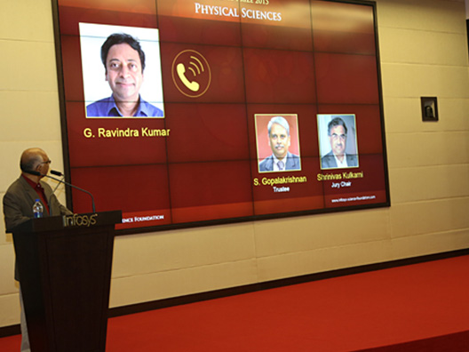 K Dinesh looks on as the winner in Physical Sciences Prof. G Ravindra Kumar responds